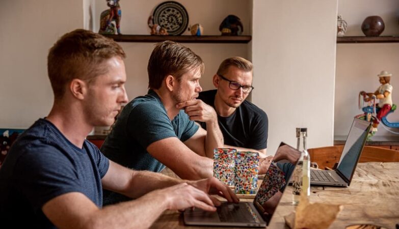 Three young SEO Problem-Solvers discussing, watching at the laptop screen