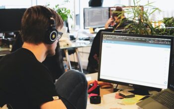 Professional using computer with headphones in open office space – illustrating the efficient SaaS SEO strategies discussed in the comprehensive roadmap for maximizing conversions effortlessly.